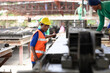 © eakarat - Young engineers and foremen wearing hard hats in a factory are inspecting the work on a construction site and pouring cement.