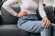 © Yura Yarema - Abdomen inflammation, menstrual period. Flatulence ulcer young woman sitting on sofa holding on belly, stomach pain from food poisoning, abdominal pain and digestive problem, gastritis or diarrhea