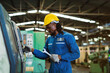 © KANGWANS - A man in a blue jumpsuit is working on a machine. He is wearing a yellow helmet and gloves