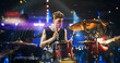 © Gorodenkoff - Handsome Young Drummer Performing on Concert Stage with His Band Members, Surrounded by Falling Confetti and Pulsating Visuals. Young Musicians Showcasing Their Skills and Energy. Slow Motion Footage
