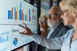 © artchvit - A group of professionals reviews data visualizations on a screen, smiling as they discuss trends and insights focused on financial literacy and retirement planning in a modern office environment.