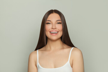 Wall Mural - Laughing brunette woman with glowing skin, subtle makeup and a gentle smile. Young model posing, portrait