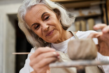 A skilled artisan meticulously shapes clay while smiling in her inviting craft space.