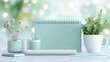 © Blue Ha Waii - AI - Minimalist Desk Setup with Mint Green Notebook, Craft Supplies, and Potted Plant Against a Soft Bokeh Background for Calming Work Environment