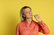 © New Africa - Young woman eating tasty rainbow sour belt on yellow background