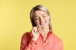 © New Africa - Young woman eating tasty rainbow sour belt on yellow background