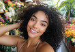 © TENphoto - Young woman smiling in a flower shop surrounded by vibrant blooms during daylight hours