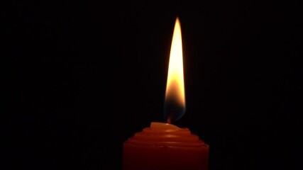 Wall Mural - Lighter ignites a red candle wick against a black background, creating a warm and cozy atmosphere with flickering flame