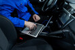 © zphoto83 - A technician works on a laptop inside a vehicle while parked in a service area during the day