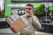 © Miljan Živković - senior man stand in front company with package and talk on cellphone