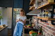 © Geber86 - Young woman holding smartphone in modern kitchen
