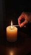 © Lexi - Person lighting a candle with a match in a dimly lit room, creating a warm ambiance
