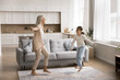 © fizkes - Carefree granny dancing together with little granddaughter in cozy living room, feel untroubled, listening favourite music on pastime, weekend leisure at home. Hobby, fun, active lifestyle of family