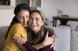 © fizkes - Happy retired older Latin mother and young adult daughter tightening each other with closed eyes, smiling, laughing, hugging with love, affection, care, trust, enjoying family friendship