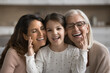 © fizkes - Three generations of women portrait. Preschooler girl, mother and grandmother sit on sofa, enjoy moments of warmth and harmony. Multigenerational family ties, connection between diverse generations