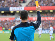 © Vectplus - Referee showing a yellow card during a tense soccer match at a stadium filled with excited fans