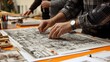 © Enggal Pitoyo - Hands arranging pins on a large architectural drawing.