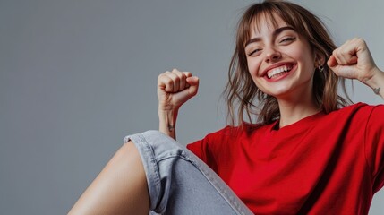 A woman sits on a chair wearing a red shirt, suitable for use in editorial or commercial contexts