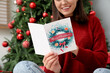© Pixel-Shot - Happy young woman reading greeting card near decorated Christmas tree at home
