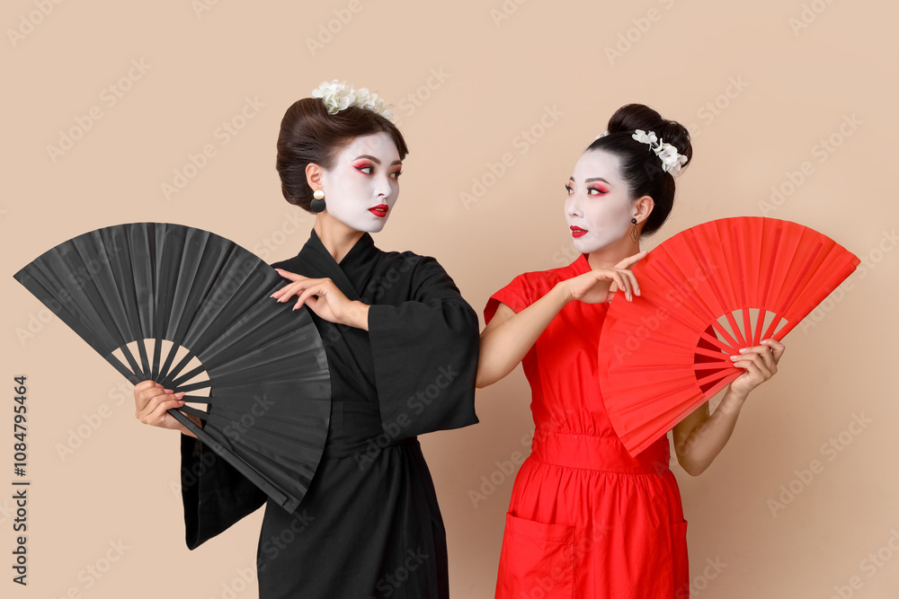 Beautiful young geishas with fans on beige background