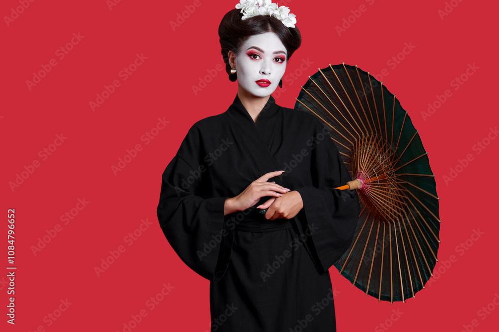 Beautiful young geisha with parasol on red background