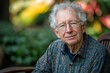 © ardanz - A smiling elderly man with curly hair seated outdoors in nature.