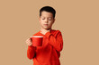 © Pixel-Shot - Ill little Asian boy with sore throat and cup of tea on beige background
