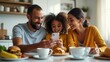 © SerPak - A joyful family shares a breakfast moment, smiling and looking at a smartphone. The table is set with delicious food, including pastries and drinks, as laughter fills the air in their cozy kitchen.