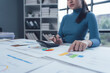© Kritdanai - Focused on Financial Growth: An Asian businesswoman meticulously analyzes graphs and charts, utilizing a calculator to navigate the intricacies of financial planning.