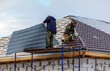 © schankz - Two men are working on a roof, one of them is wearing a blue jacket