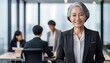 © fotoluigi868 - A senior Asian woman smiles confidently in a black suit, surrounded by a modern office envi_1(117)