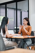 © Satori Studio - Two Women Engaged in a Business Meeting at a Modern Office with a Laptop and Documents on the Table