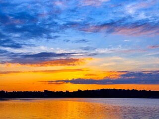 Wall Mural - vivid colorful color of sunset with clouds.sunset with mountain above lake reflection in water.