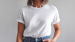 © Tom - A young woman with short, light brown hair poses confidently in a white t-shirt and high-waisted jeans against a light background.