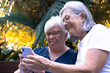 © luciano - Smiling senior old couple of women in outdoors in the park in a sunny day enjoying free time and nature