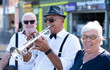 © luciano - Portrait of jazz artist in open air concert playing among passers by. Old man in black hat and sunglasses playing trumpet in street.