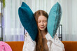 © Andrii Iemelianenko - Repair work at neighbours. Irritated girl child relaxing on couch cover ears with pillows annoyed by noisy neighbors suffer from headache wish silence. Thin walls at home flat without sound insulation