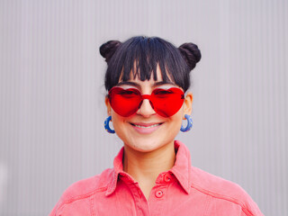  latin america woman smiling, Love sunglasses Close up portrait, pink clothes. Red shape heart eyeglasses, brunette buns hair. Valentine day 14 february concept. Happy expression. Ecuador beauty