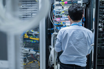 Computer engineer is setting up network in server room,Systems Maintenance Technician,Male engineer working in server room at modern data center