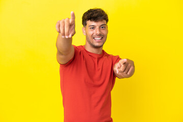 Sticker - Young caucasian handsome man isolated on yellow background pointing front with happy expression