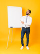 © luismolinero - Full-length shot of businessman giving a presentation on white board over isolated yellow background happy and smiling