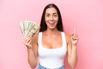 Wall Mural - Young caucasian woman taking a lot of money isolated on pink background pointing up a great idea