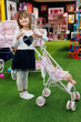 © Studio Peace - Cute little girl is playing with a doll and a stroller in a modern playroom.
