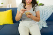 © AntonioDiaz - Closeup of a teenager girl eating nuts from a glass bowl sitting on a sofa, having allergy problems