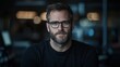 © Lifestyle Images - A man with glasses and a beard is sitting in a dark room