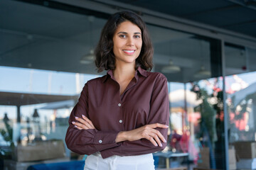 portrait of beautiful successful hispanic young business woman with crossed arms smiling at camera. 
