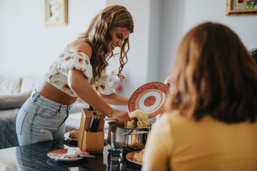 Poster - A smiling young woman serves pasta to friends at a cozy home gathering, creating a warm and welcoming dining experience.