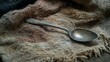 © Thavesak - Resilience in the Details: Close-up of Old Spoon Beside Tattered Blanket, Symbolizing Survival and Endurance
