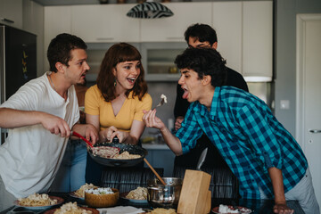 Wall Mural - A group of friends share a joyful meal together in a kitchen setting, highlighting the essence of friendship, laughter, and shared moments over a delicious dining experience.