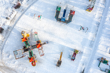 snow-covered colorful playground in winter park after snowfall. aerial photography with drone.